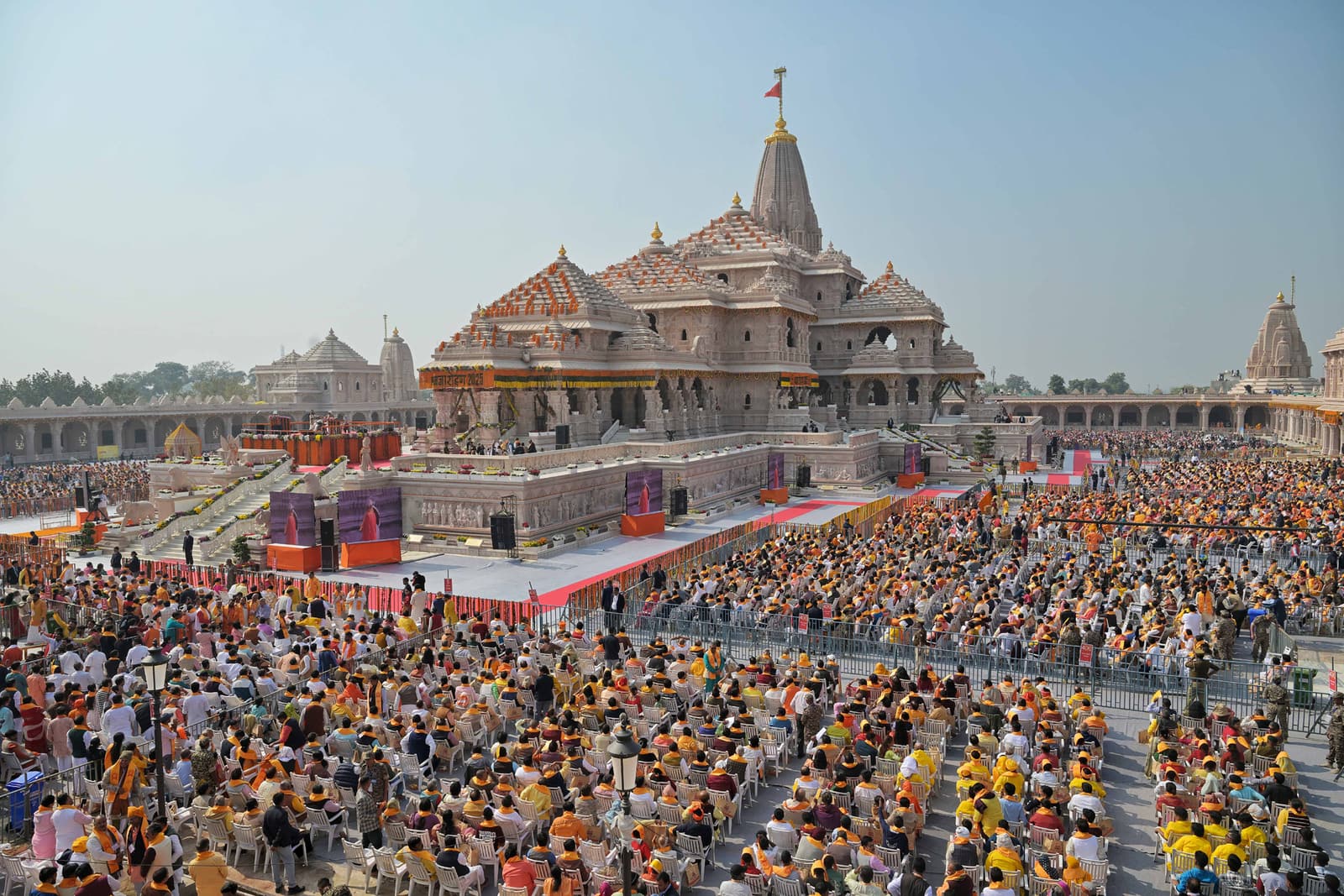 ઉત્સવના દિવસે દર્શનાર્થીઓથી ભરેલા પ્રાંગણની પેલે પારથી દેખાતું અયોધ્યાનું રામ મંદિર